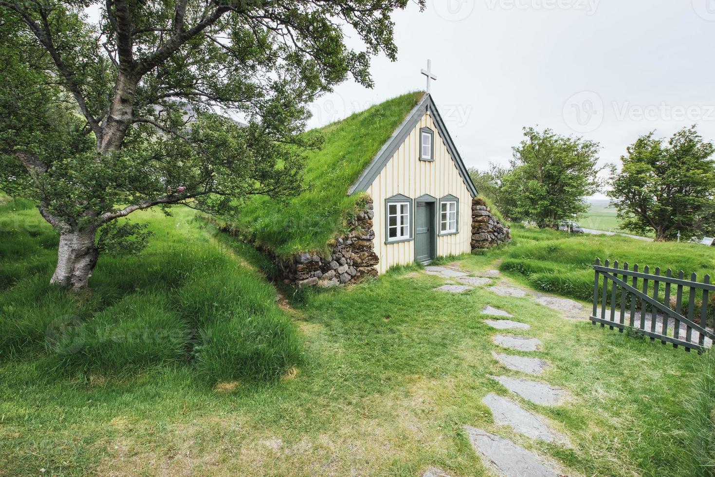 en liten träkyrka och kyrkogård hofskirkja hof, skaftafell island. naturskön solnedgång genom trädkronor foto