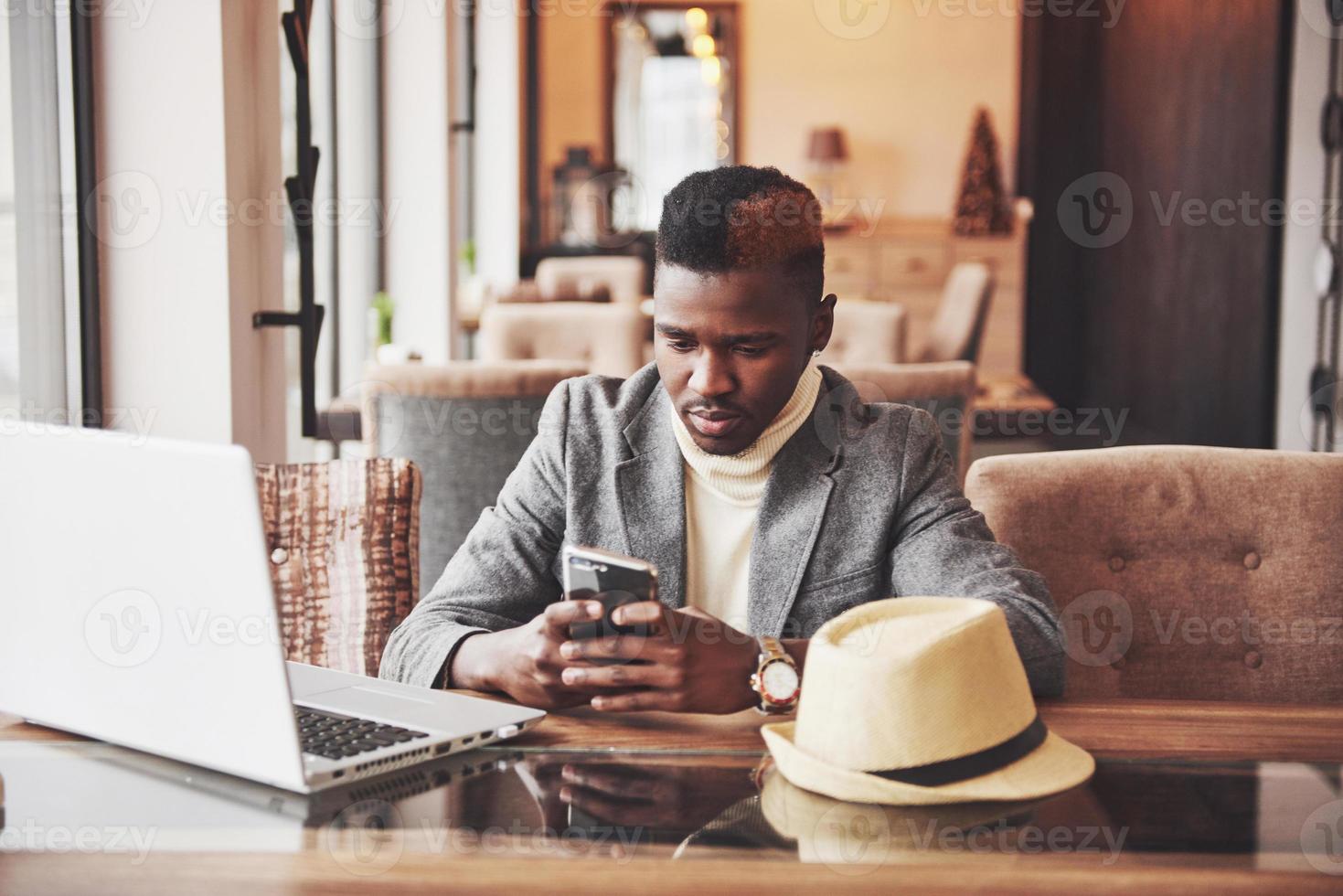 porträtt av afroamerikansk man som sitter på ett café och arbetar på en bärbar dator foto