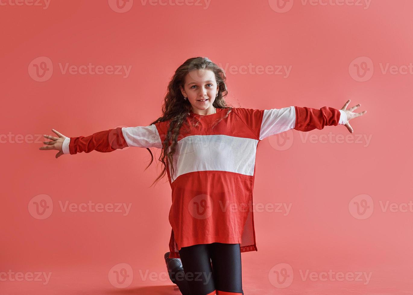 ung vacker söt flicka som dansar på röd bakgrund, modern smal hip-hop stil tonårsflicka som hoppar foto