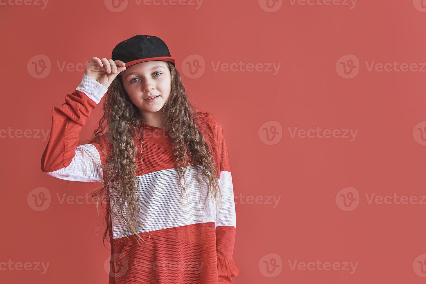 ung vacker söt flicka som dansar på röd bakgrund, modern smal hip-hop stil tonårsflicka som hoppar foto