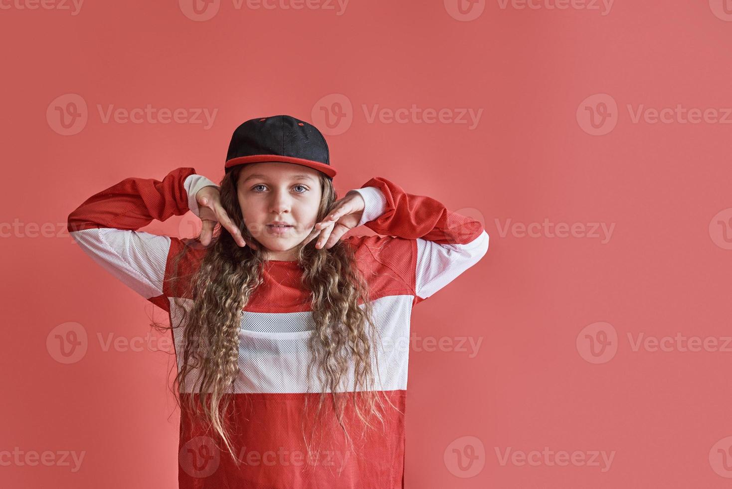 ung vacker söt flicka som dansar på röd bakgrund, modern smal hip-hop stil tonårsflicka som hoppar foto