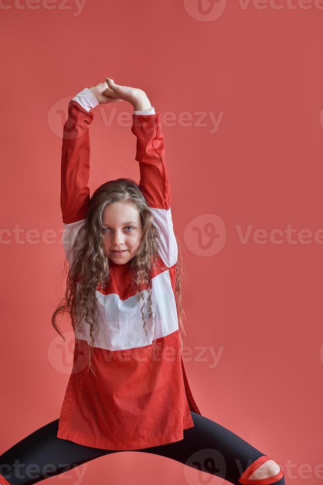 ung vacker söt flicka som dansar på röd bakgrund, modern smal hip-hop stil tonårsflicka som hoppar foto
