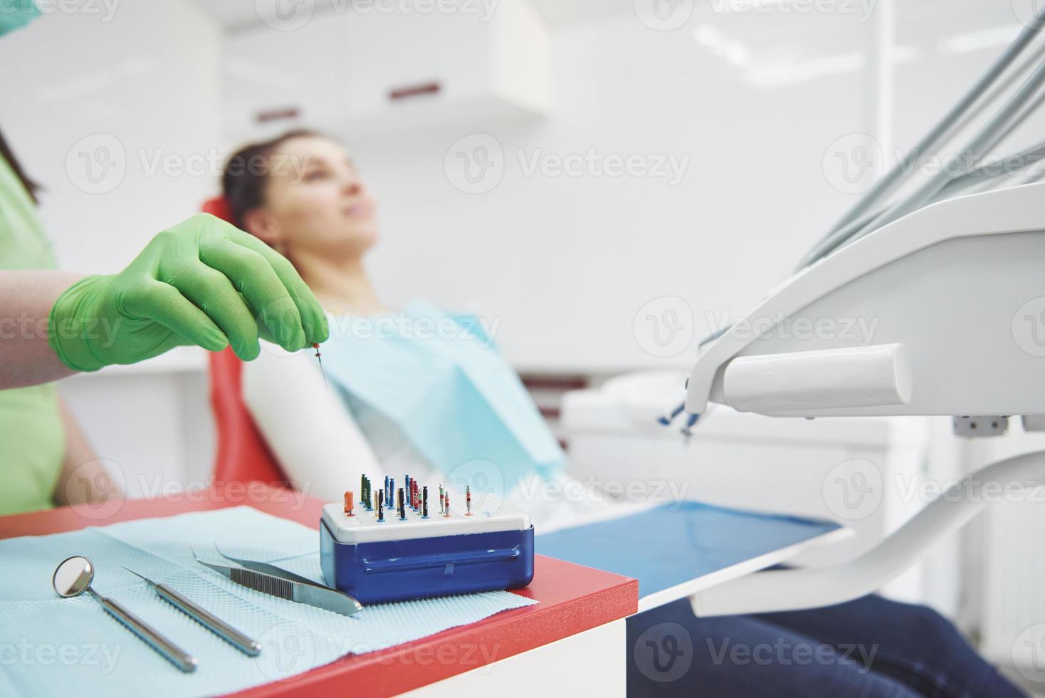 en patient på en tandklinik sitter i en stol och läkaren förbereder verktygen för behandling foto