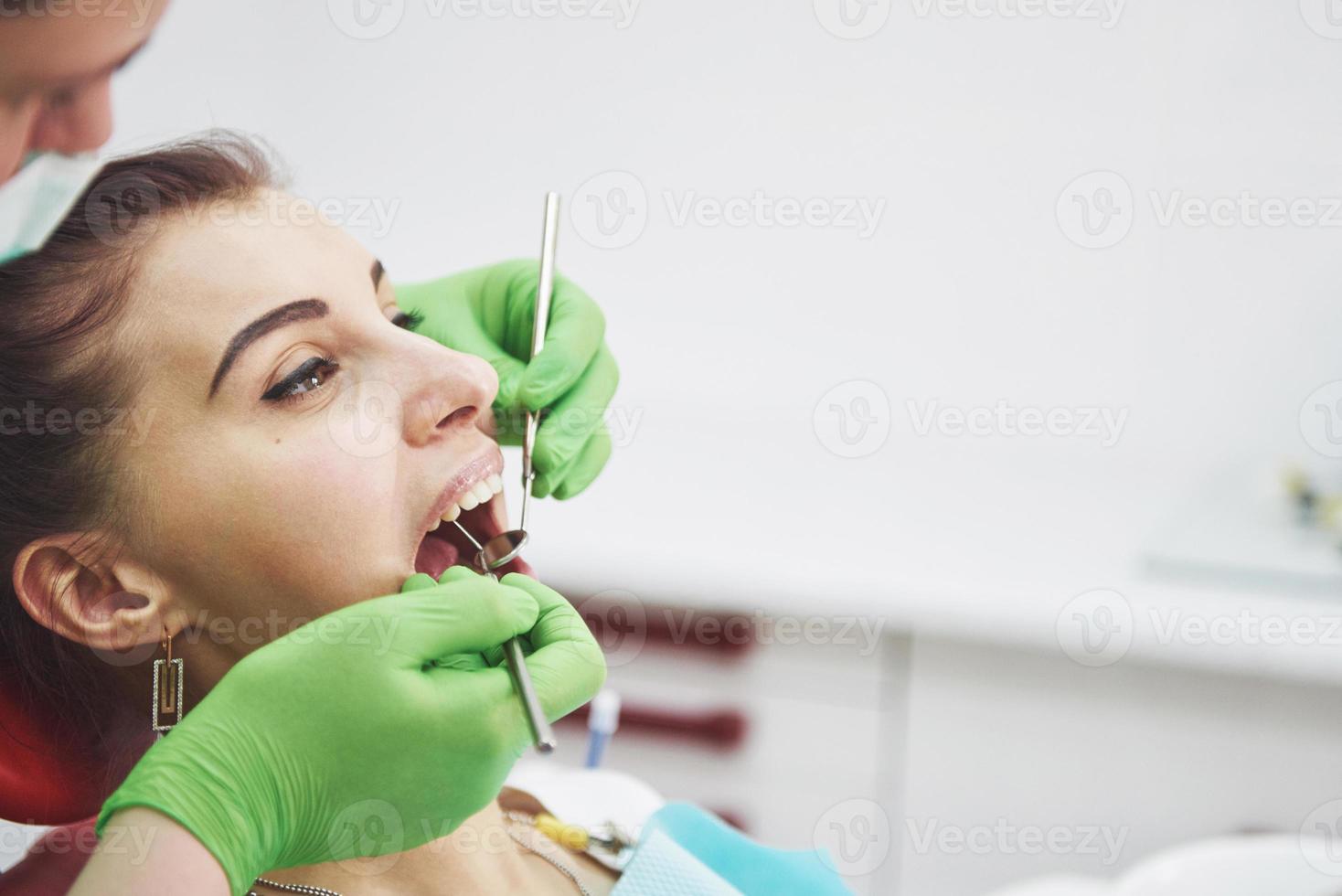 tandläkare som botar en kvinnlig patient i stomatologin. tidigt förebyggande och munhygienkoncept foto