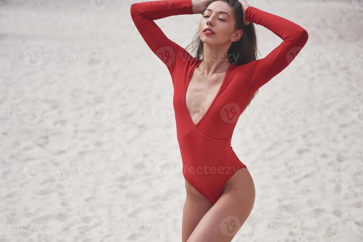 vacker ung solbränd kvinna i röd bikini poserar på stranden. sexig modellporträtt med perfekt kropp. sommar semester koncept foto