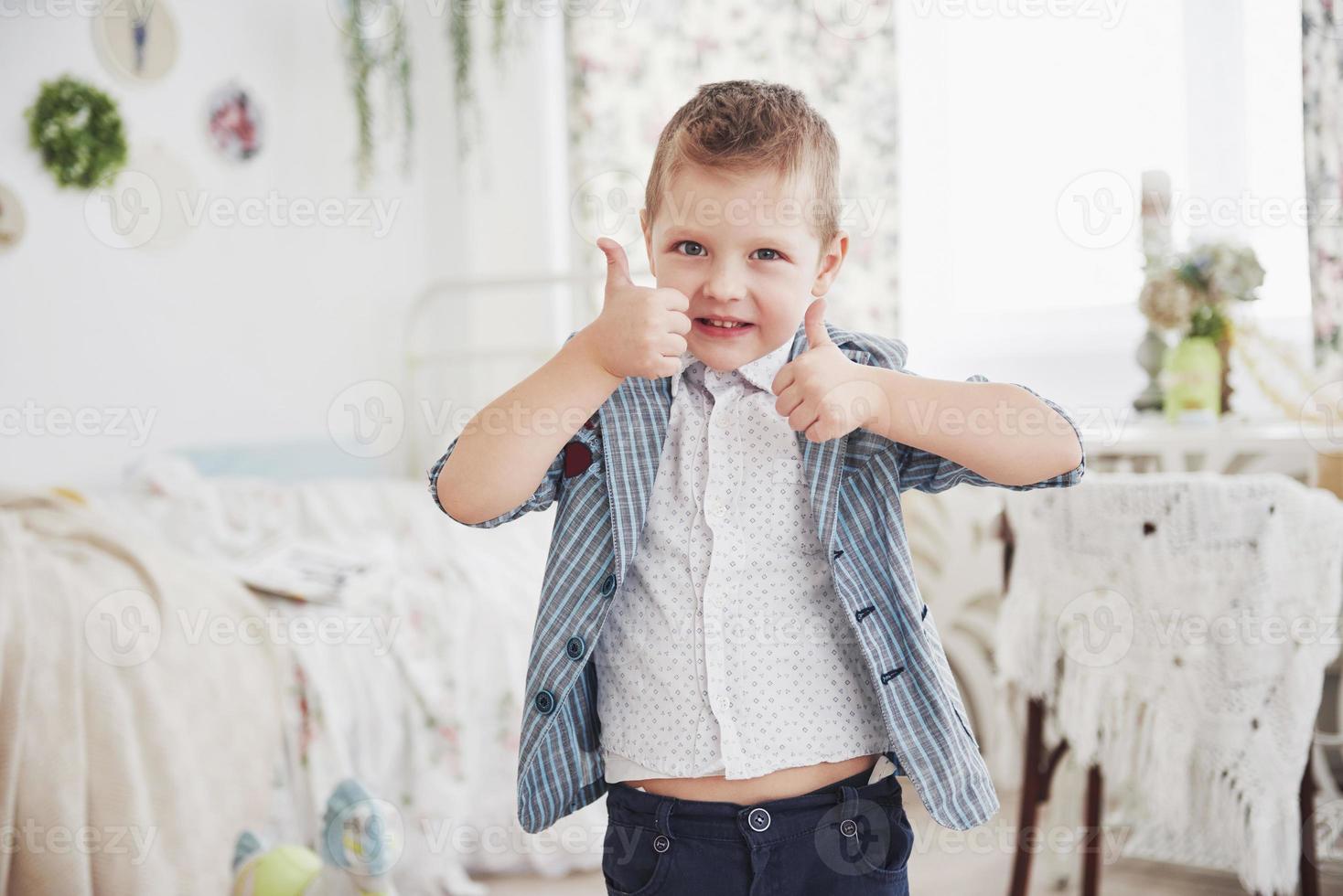en liten pojke i skolåldern höjer två tummar upp, glad. foto