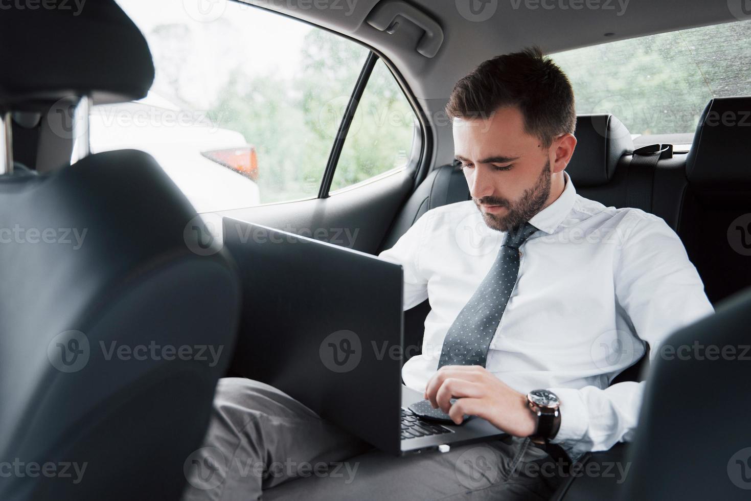 affärsman som använder bärbar dator för att arbeta i bil foto