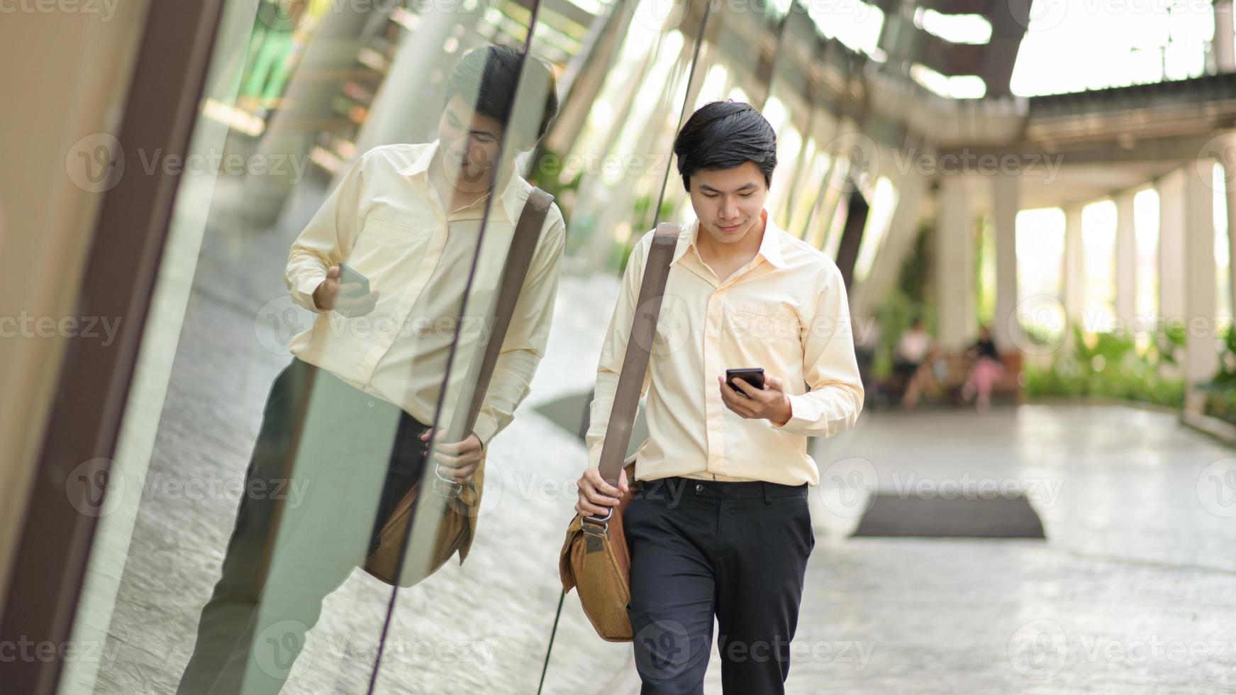 ny ung generation av företag med en axelväska titta på smarttelefonen i handen för att kontrollera arbetet. foto