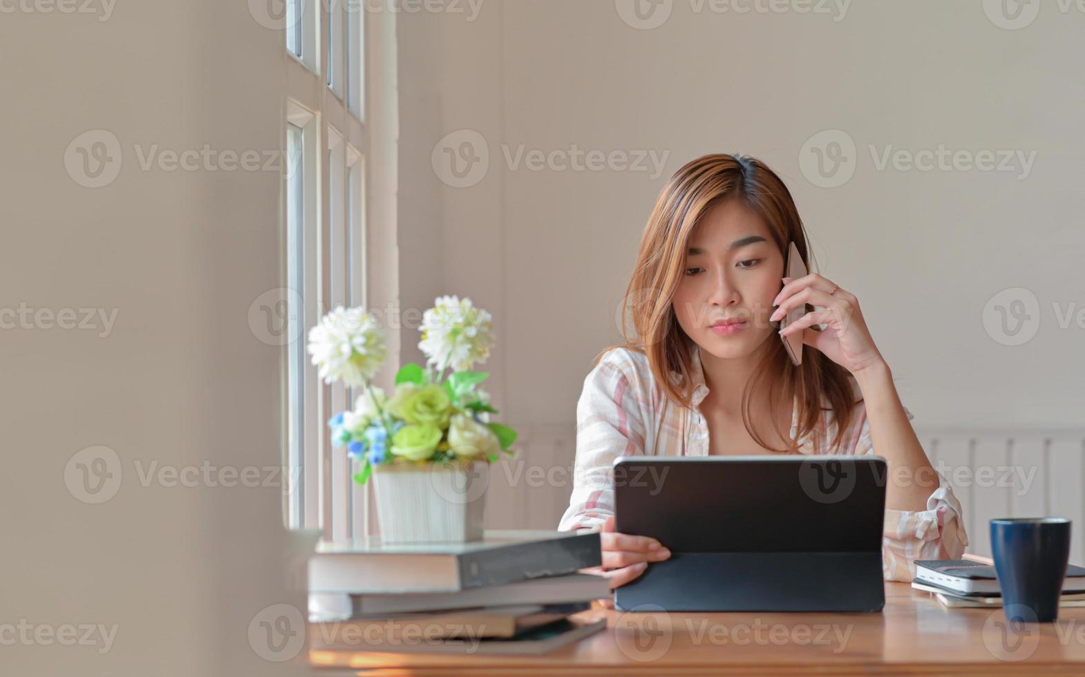 kvinnlig högskolestudent som studerar online hemma använder en smartphone för råd från en instruktör. foto