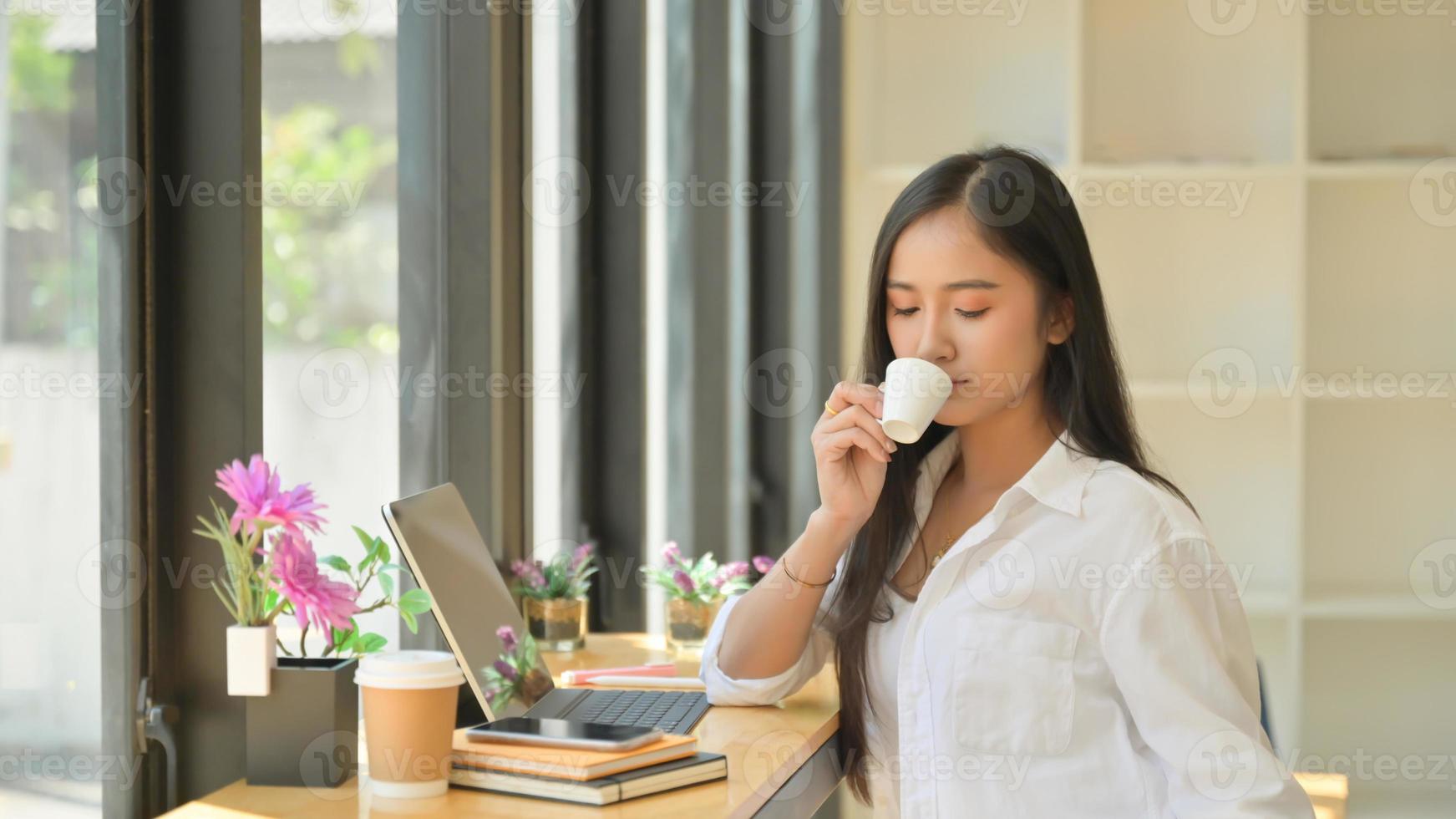 skott av unga kvinnor som dricker kaffe under en paus från projektet för att presentera för kunderna. foto