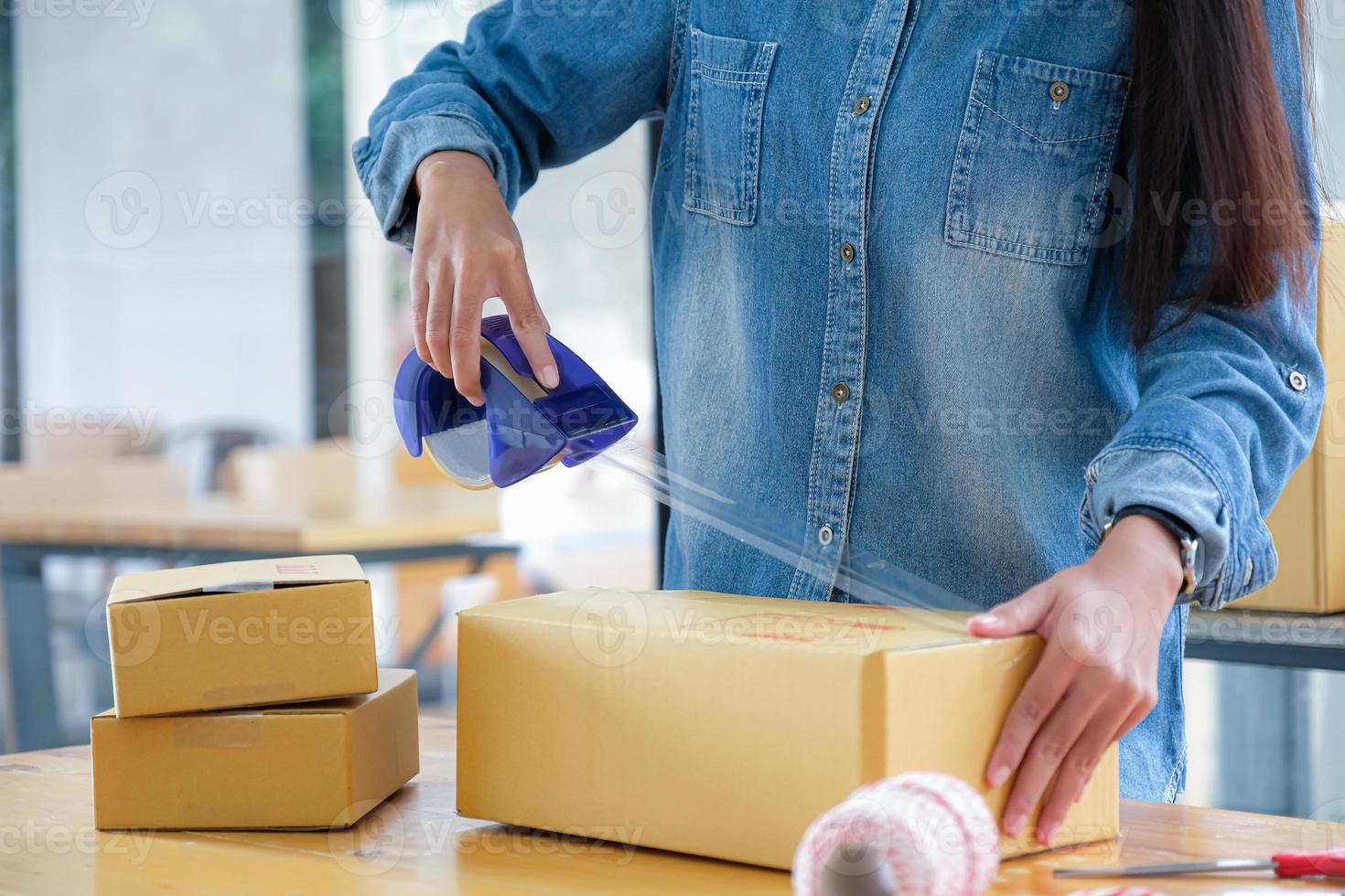 tonårsflickor packar produkter i lådor och använder klar tejp för att leverera till kunder. foto