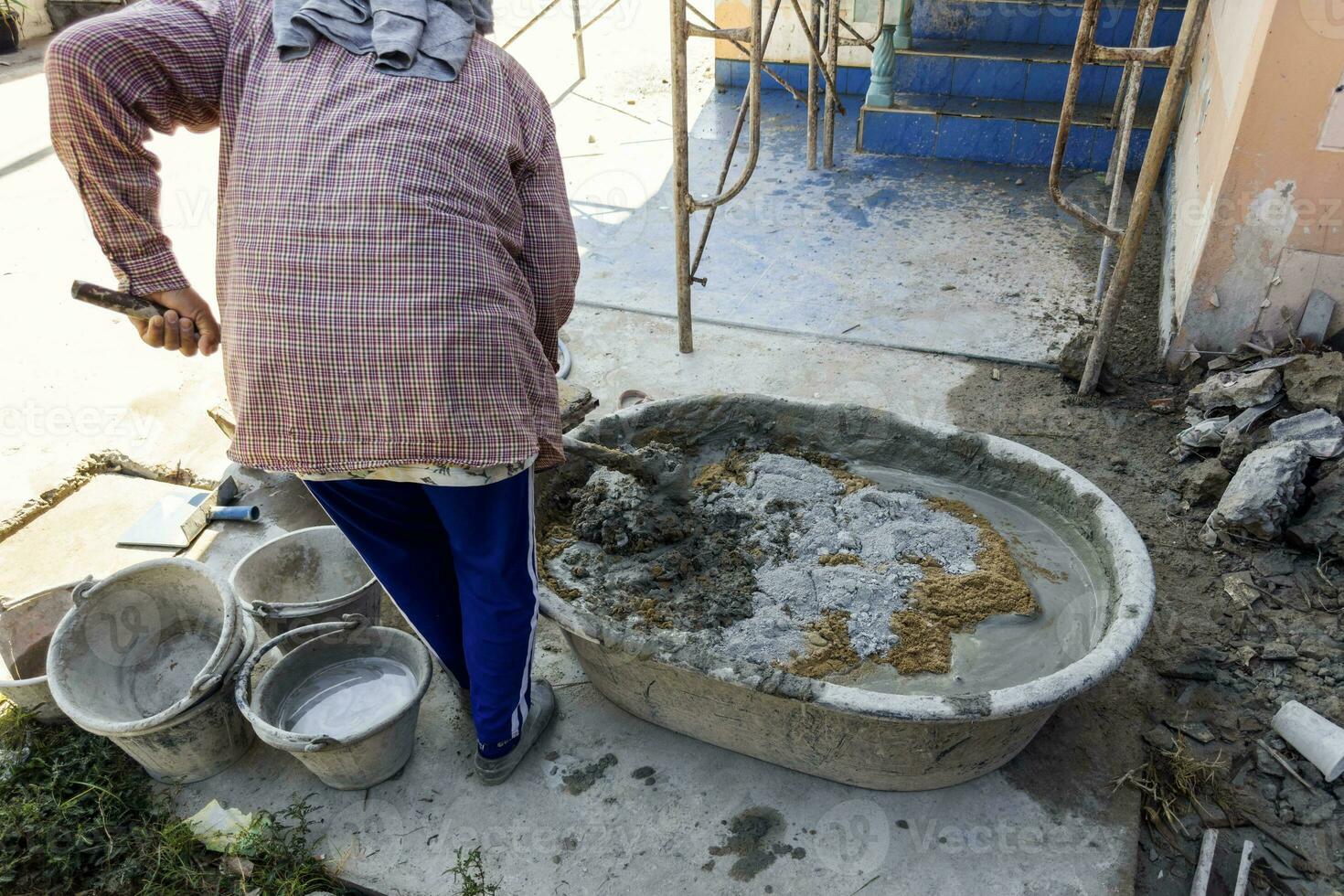 arbetstagare blandning cement betong i en plast behållare på en konstruktion webbplats företag av byggnad hus, byggnader, industri foto