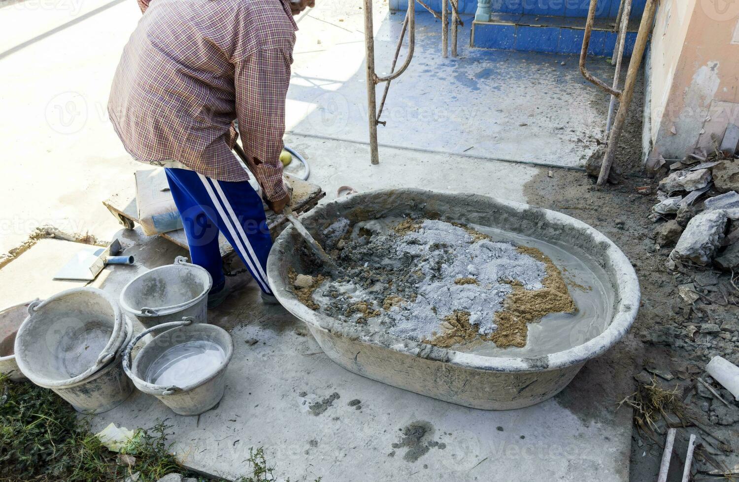 arbetstagare blandning cement betong i en plast behållare på en konstruktion webbplats företag av byggnad hus, byggnader, industri foto