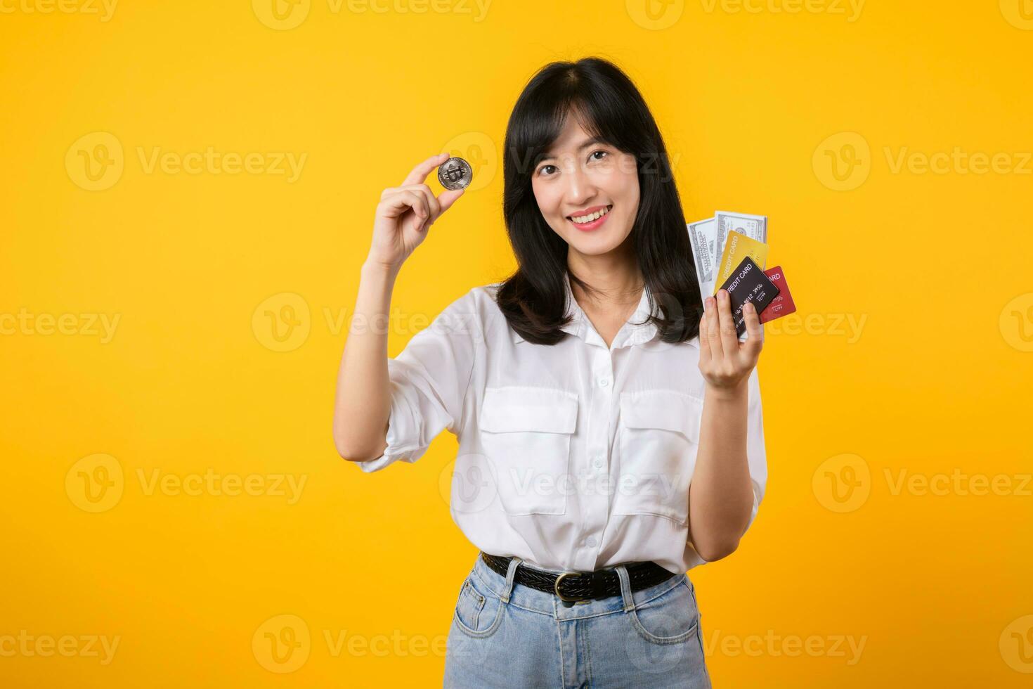 fånga de väsen av digital valuta med fantastisk porträtt av ung asiatisk kvinna självsäkert innehar digital valuta, kontanter, kreditera kort, och smartphone. de digital valuta begrepp. foto