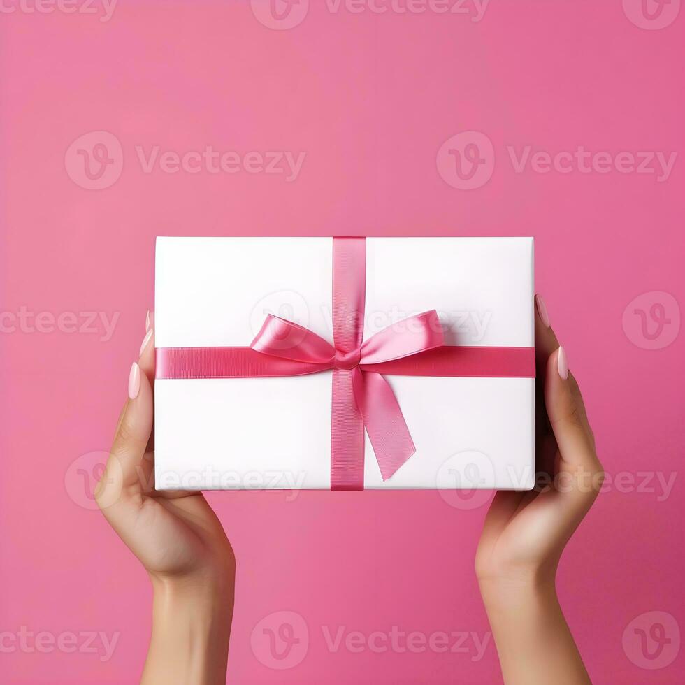 ai genererad händer innehav en gåva låda med rosa band på rosa bakgrund foto