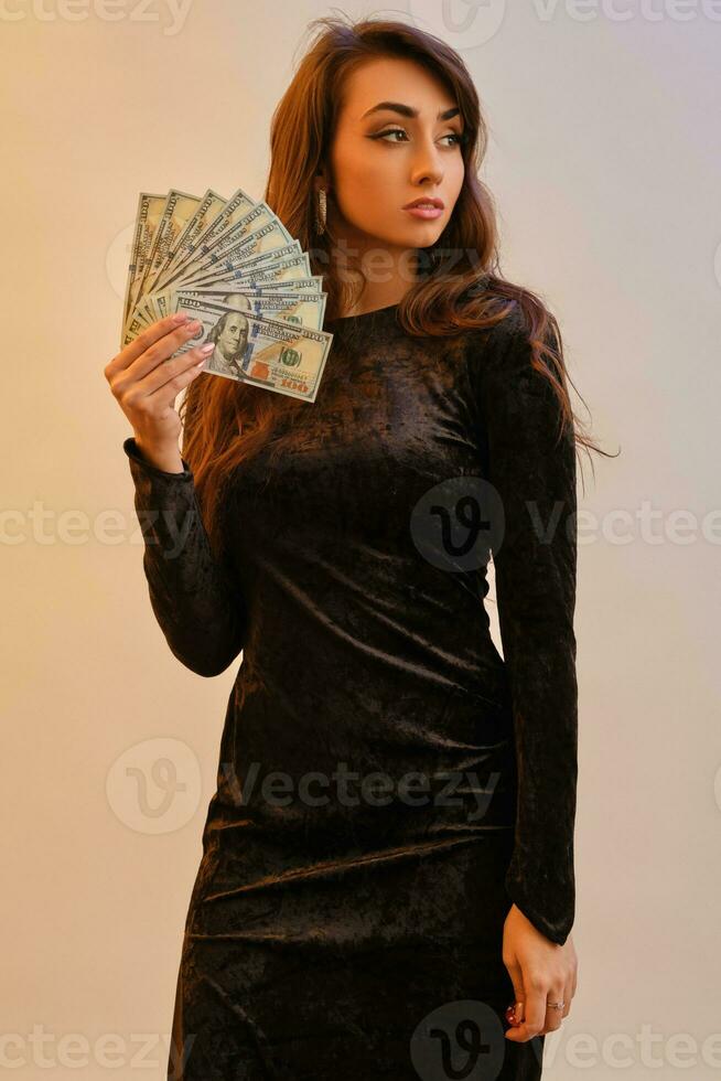 brunett flicka i svart klänning innehav två röd pommes frites och några pengar, Framställ isolerat på vit med röd bakgrundsbelysning. spelande, poker, kasino. närbild. foto