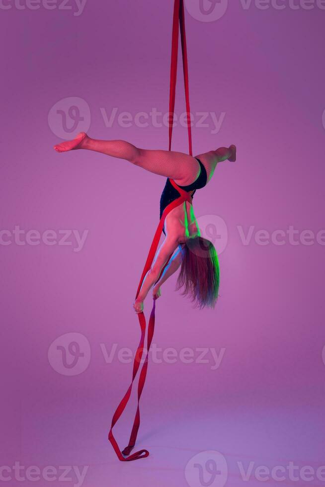 skön flicka i en svart baddräkt är utför ett akrobatisk element i studio. foto