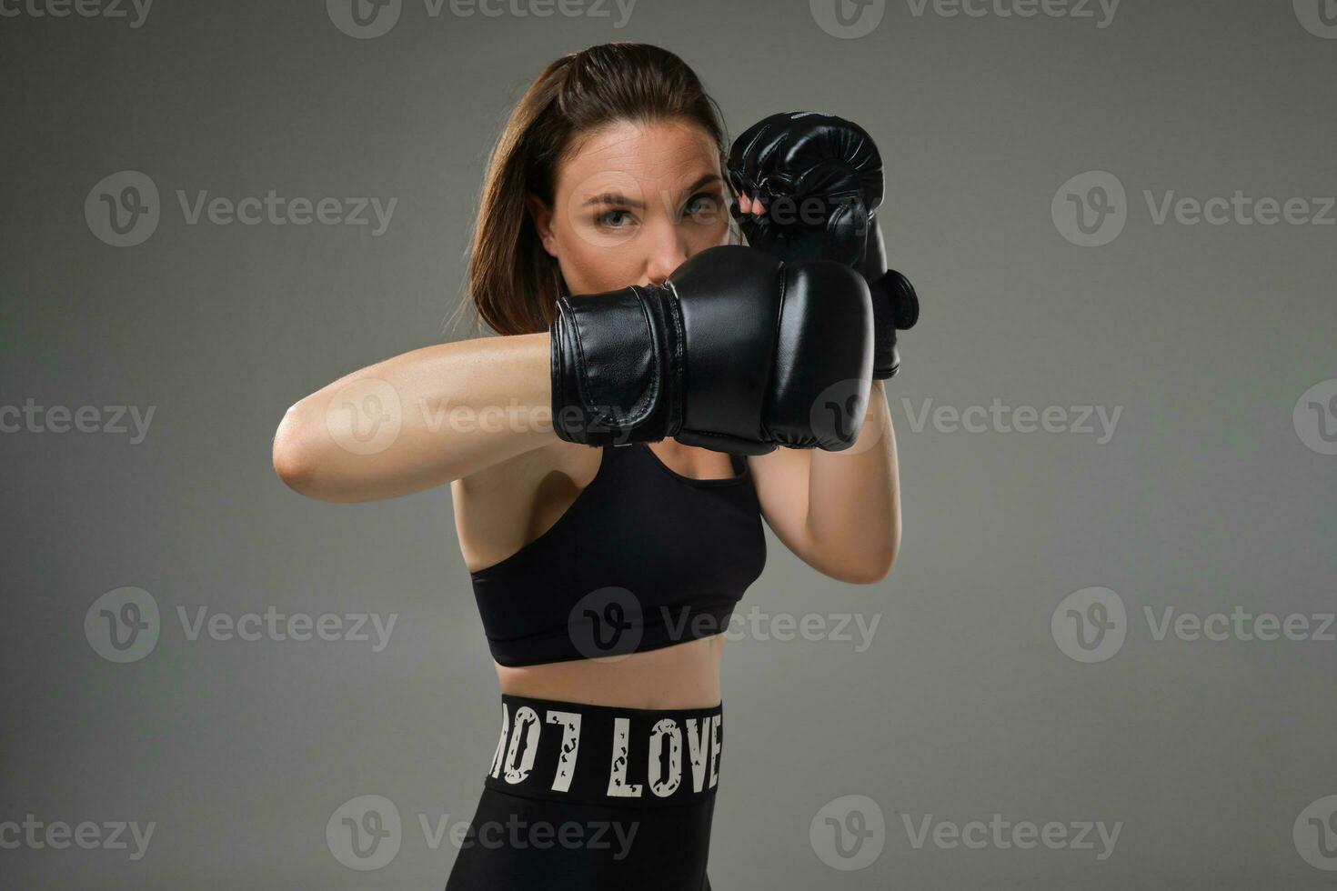 atletisk kvinna i boxning handskar är praktiserande karate i studio. foto