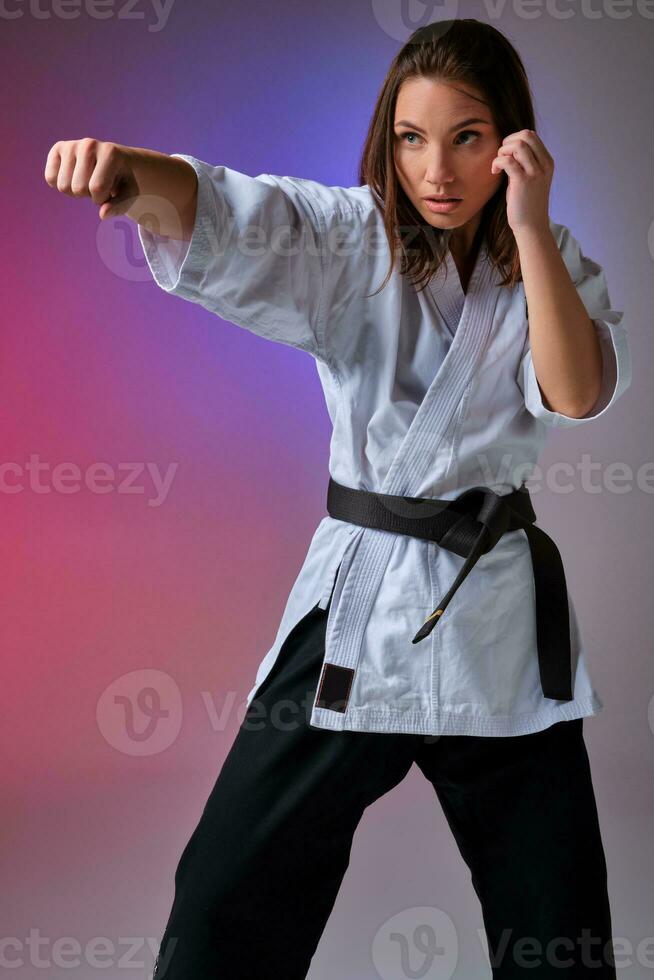 atletisk kvinna i traditionell kimono är praktiserande karate i studio. foto