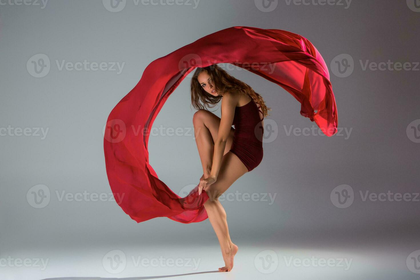 ung skön kvinna dansare i röd baddräkt Framställ på en ljus grå studio bakgrund foto