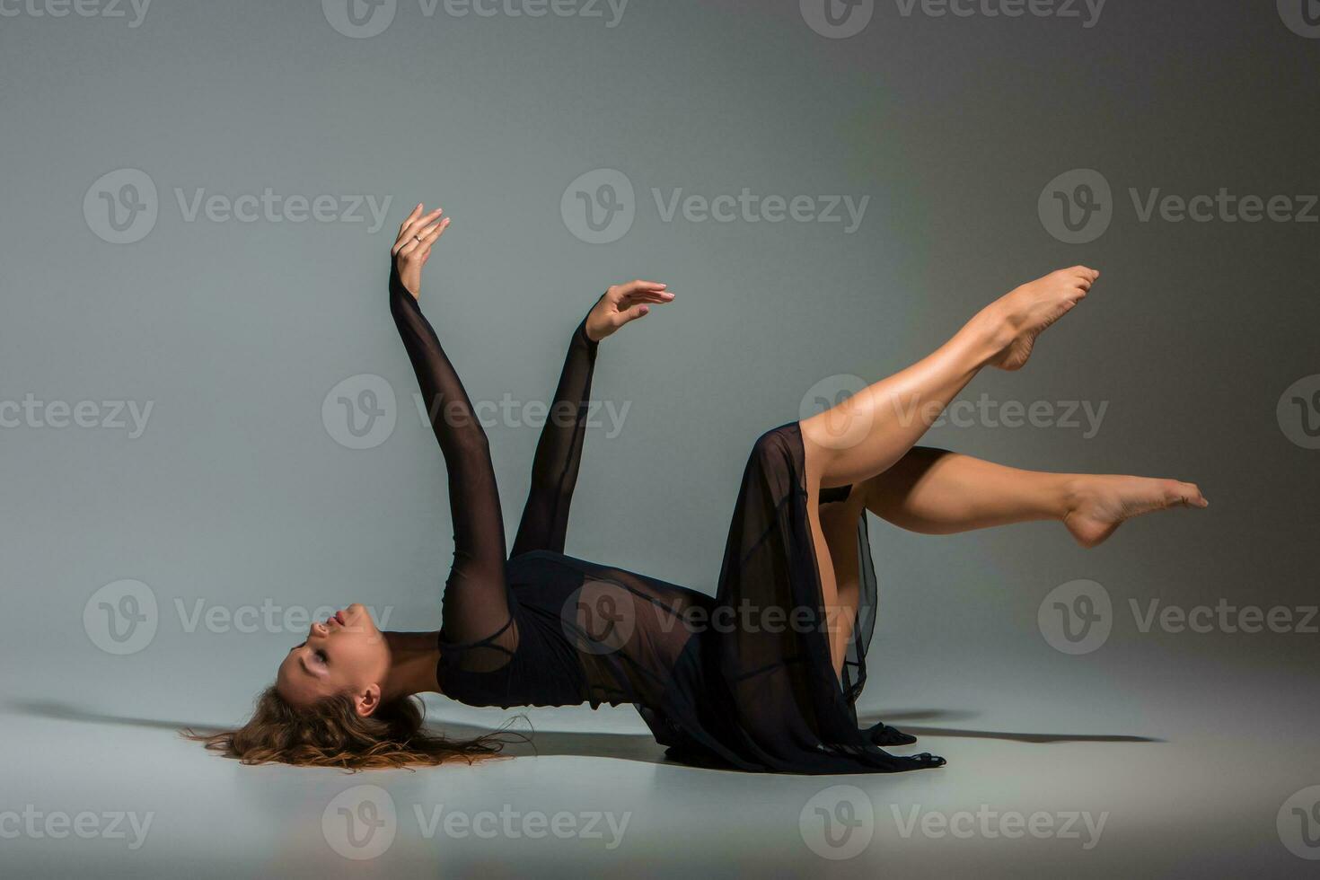 ung skön dansare i svart klänning Framställ på en mörk grå studio bakgrund foto