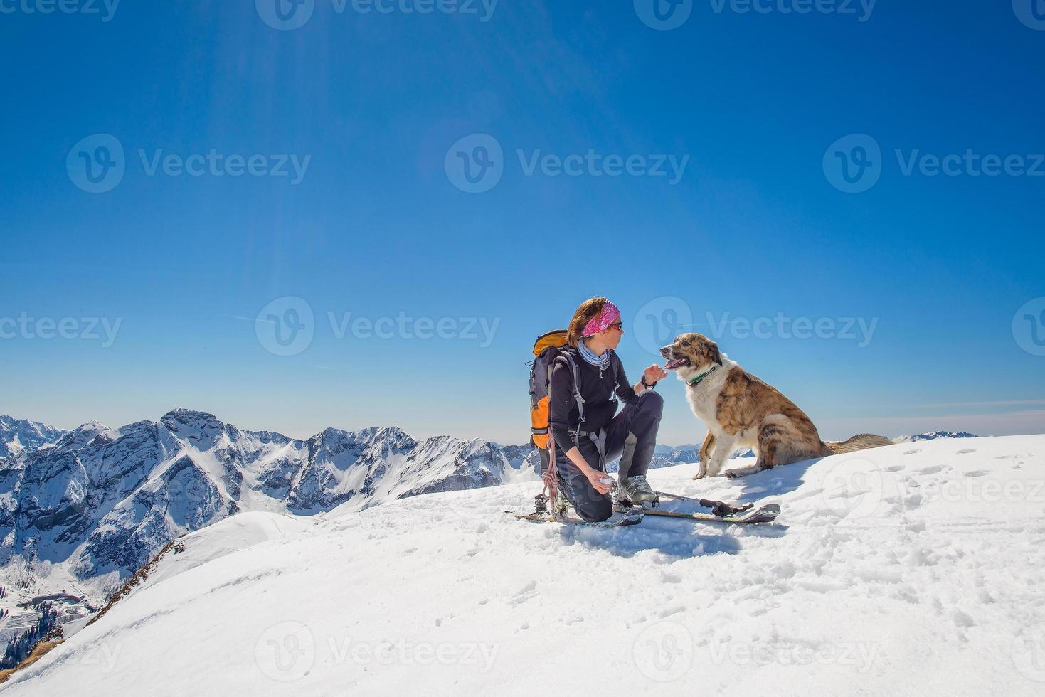 tjej skidtur med sin hund på toppen av berget foto