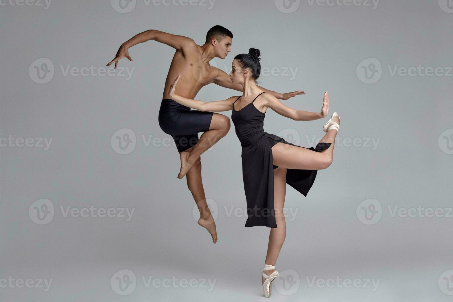 två atletisk modern balett dansare är Framställ mot en grå studio bakgrund. foto