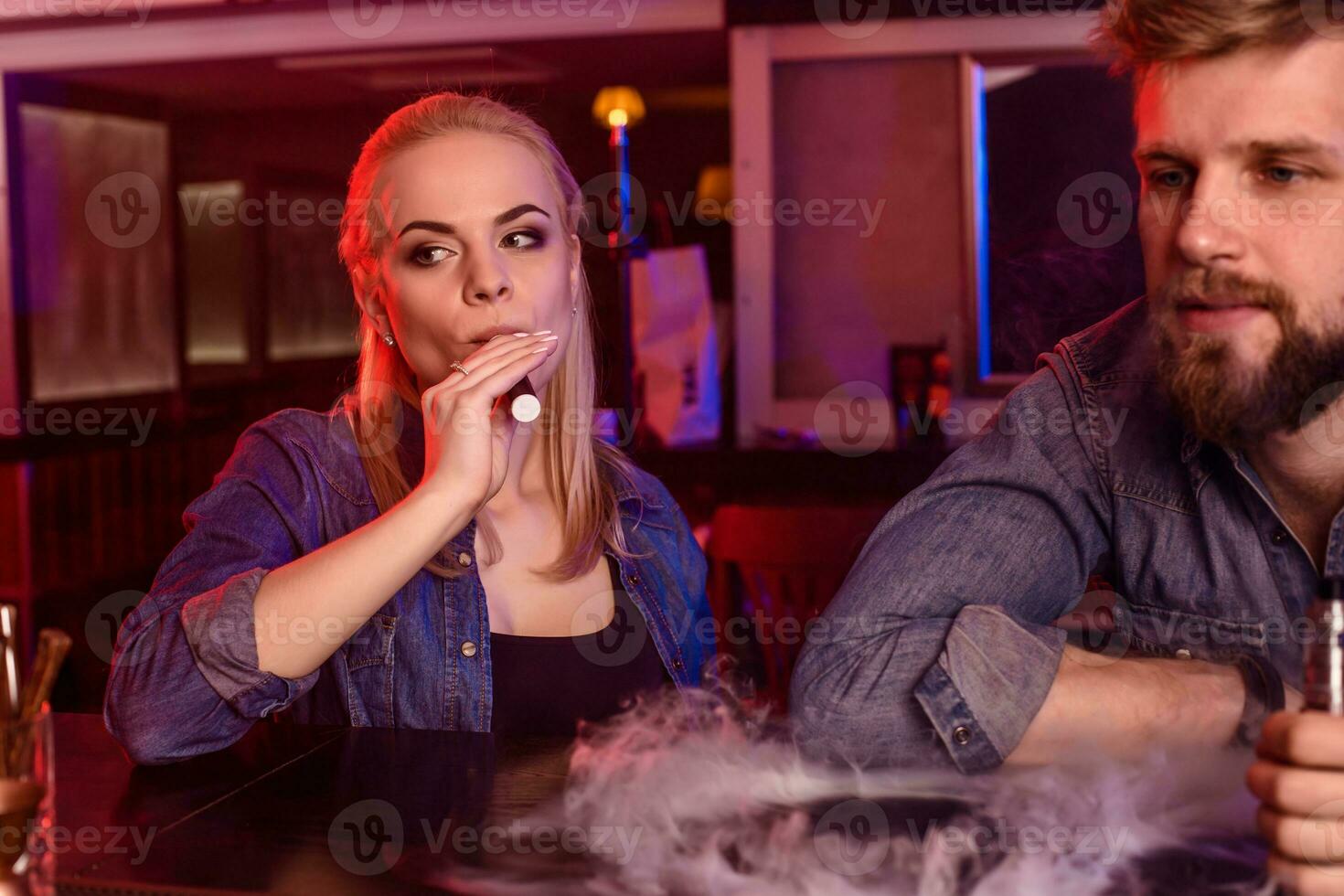 en man och kvinna rökning elektronisk cigarett i en vape bar. foto