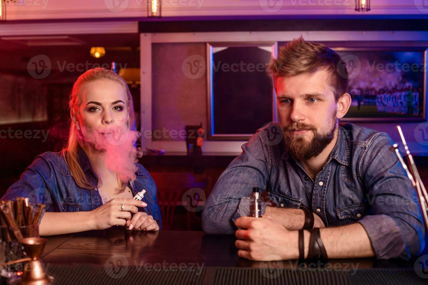 en man och kvinna rökning elektronisk cigarett i en vape bar. foto