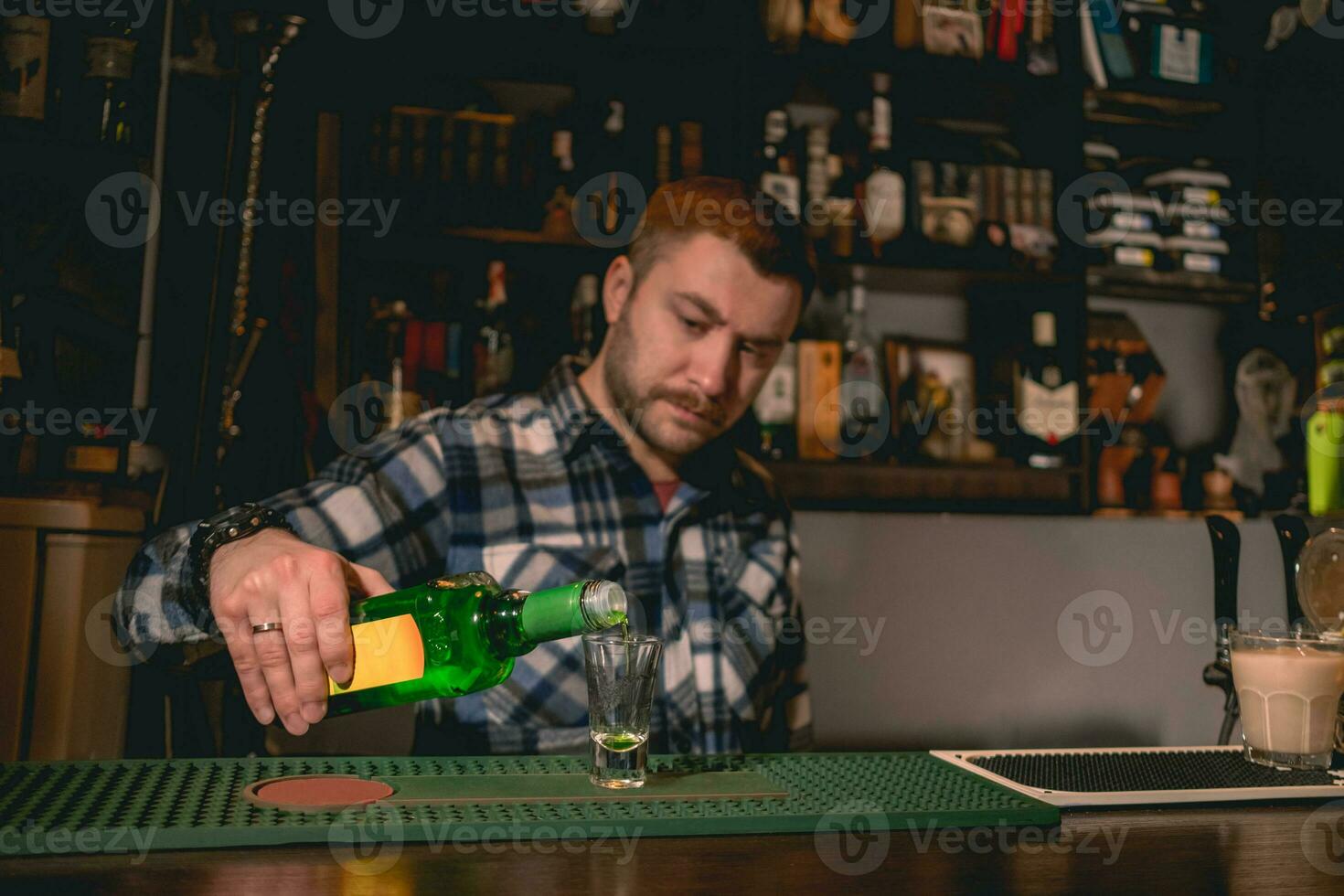 bartender häller grön banan likör in i skott glas medan framställning cocktail grön mexikansk foto