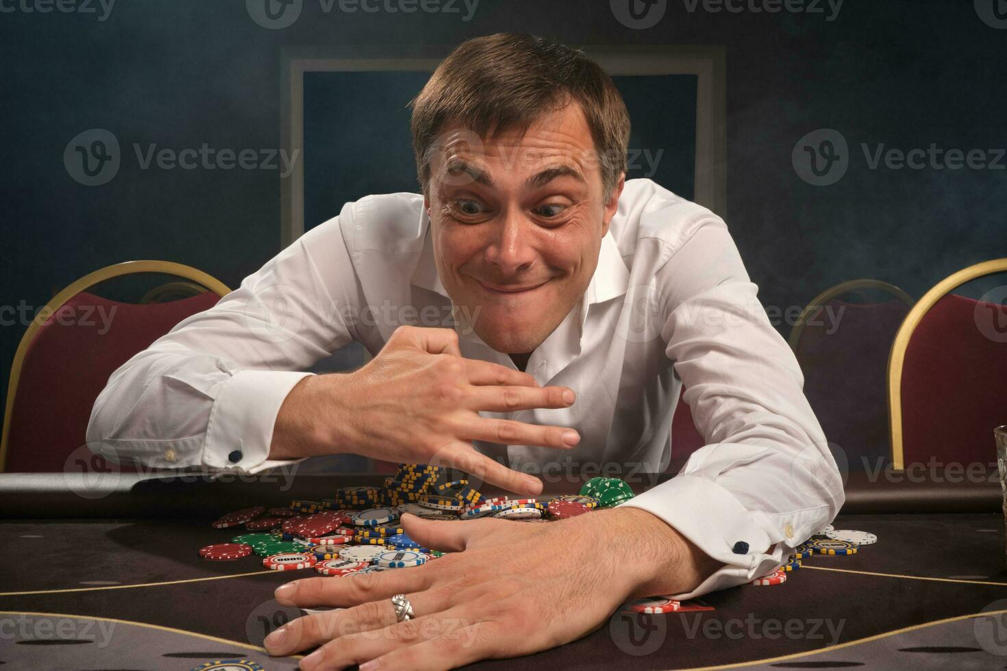 stilig emotionell man är spelar poker Sammanträde på de tabell i kasino. foto
