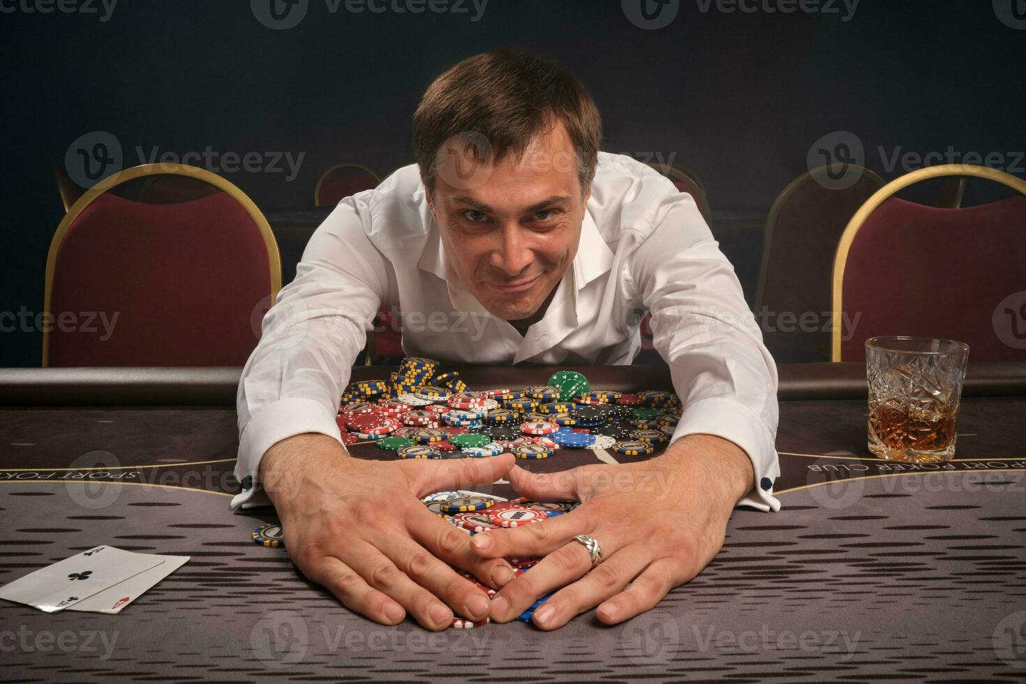 stilig emotionell man är spelar poker Sammanträde på de tabell i kasino. foto