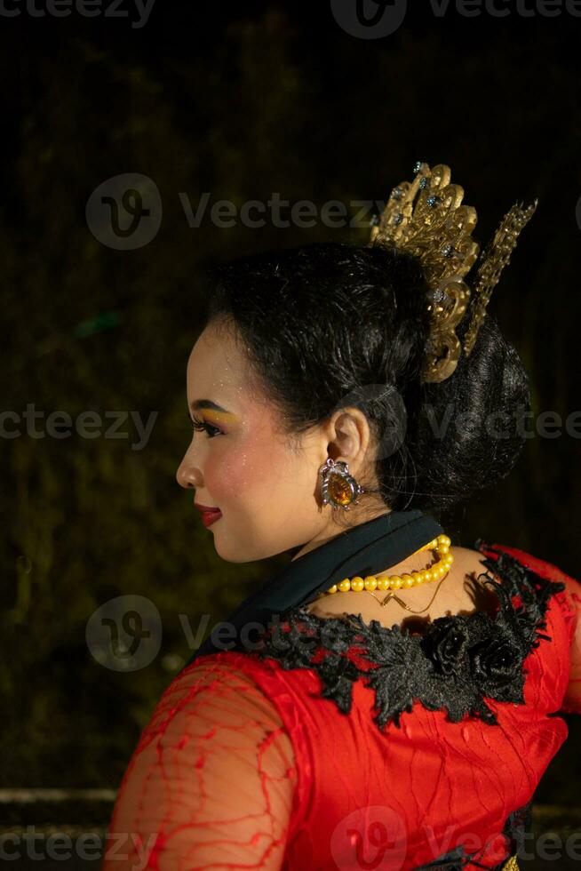 en javanese dansare bär en svart sjal och jasmin på henne huvud medan dans på skede på natt foto