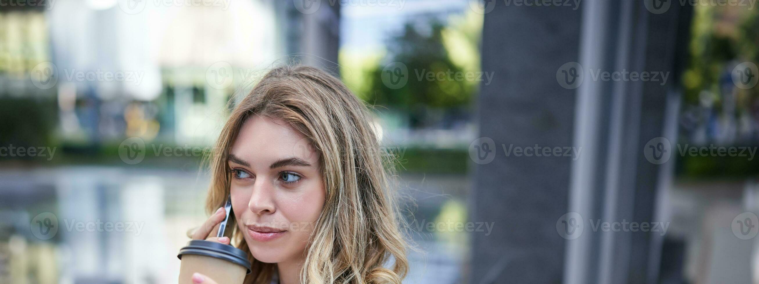 porträtt av skön kvinna talande på mobil telefon och dricka kaffe. affärskvinna drycker hämtmat i stad Centrum, kallelse någon foto