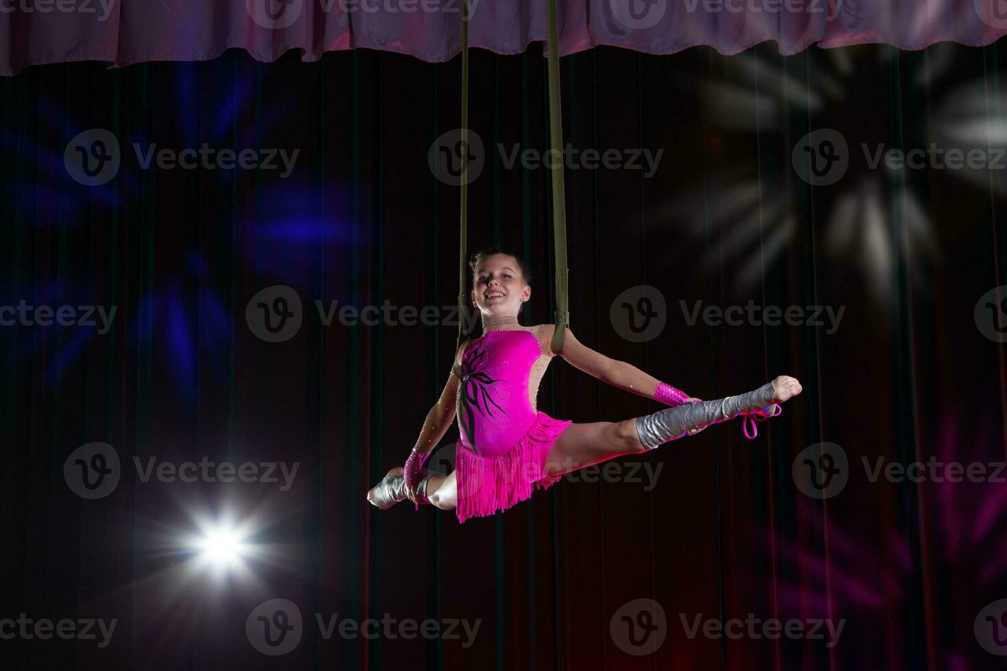 cirkus konstnär akrobat prestanda. de flicka utför akrobatisk element i de luft. cirkus gymnast på de skede foto