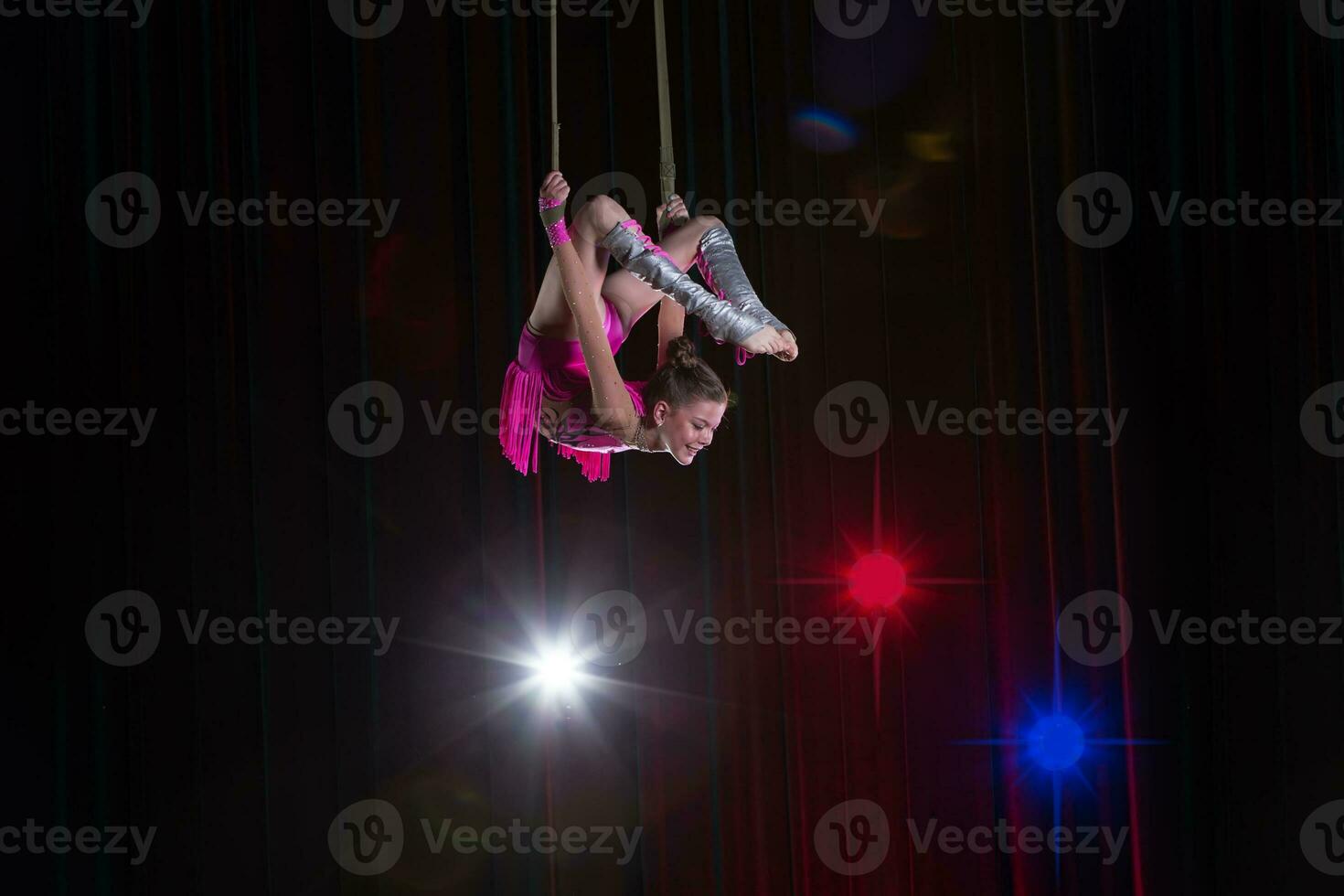 cirkus konstnär akrobat prestanda. de flicka utför akrobatisk element i de luft. cirkus gymnast på de skede foto