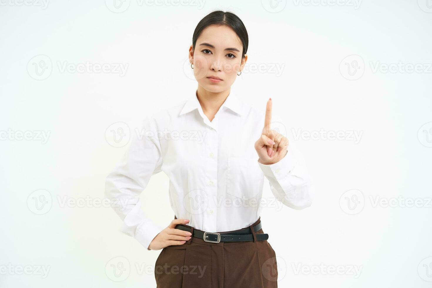 självsäker ung kvinna chef, asiatisk kvinna visar siffra ett finger, förklarar smth, står över vit bakgrund foto
