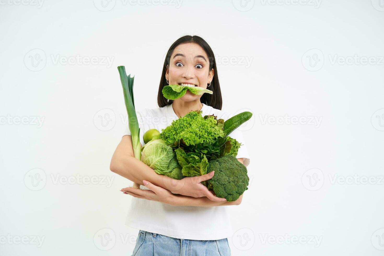porträtt av asiatisk kvinna, gumlar sallad, innehav grön organisk grönsaker, på en diet, vit bakgrund foto