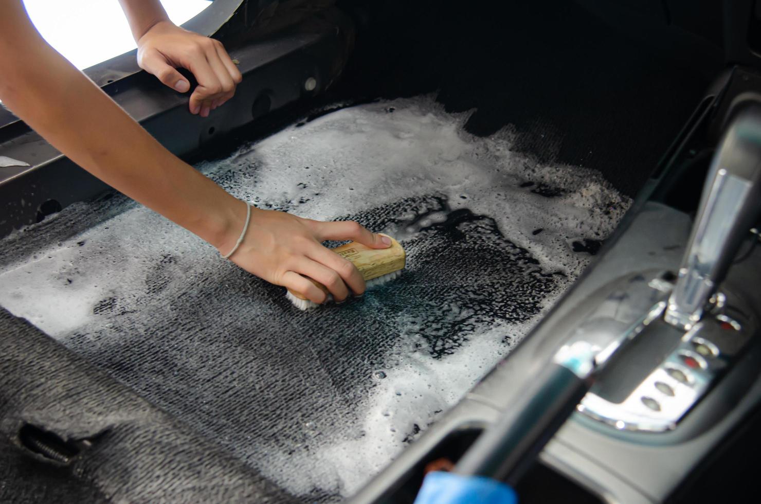 tvätta bilmattan. detaljerad på interiören i modern bil. rengör med en pensel och rengöringslösning på bilmattan. foto