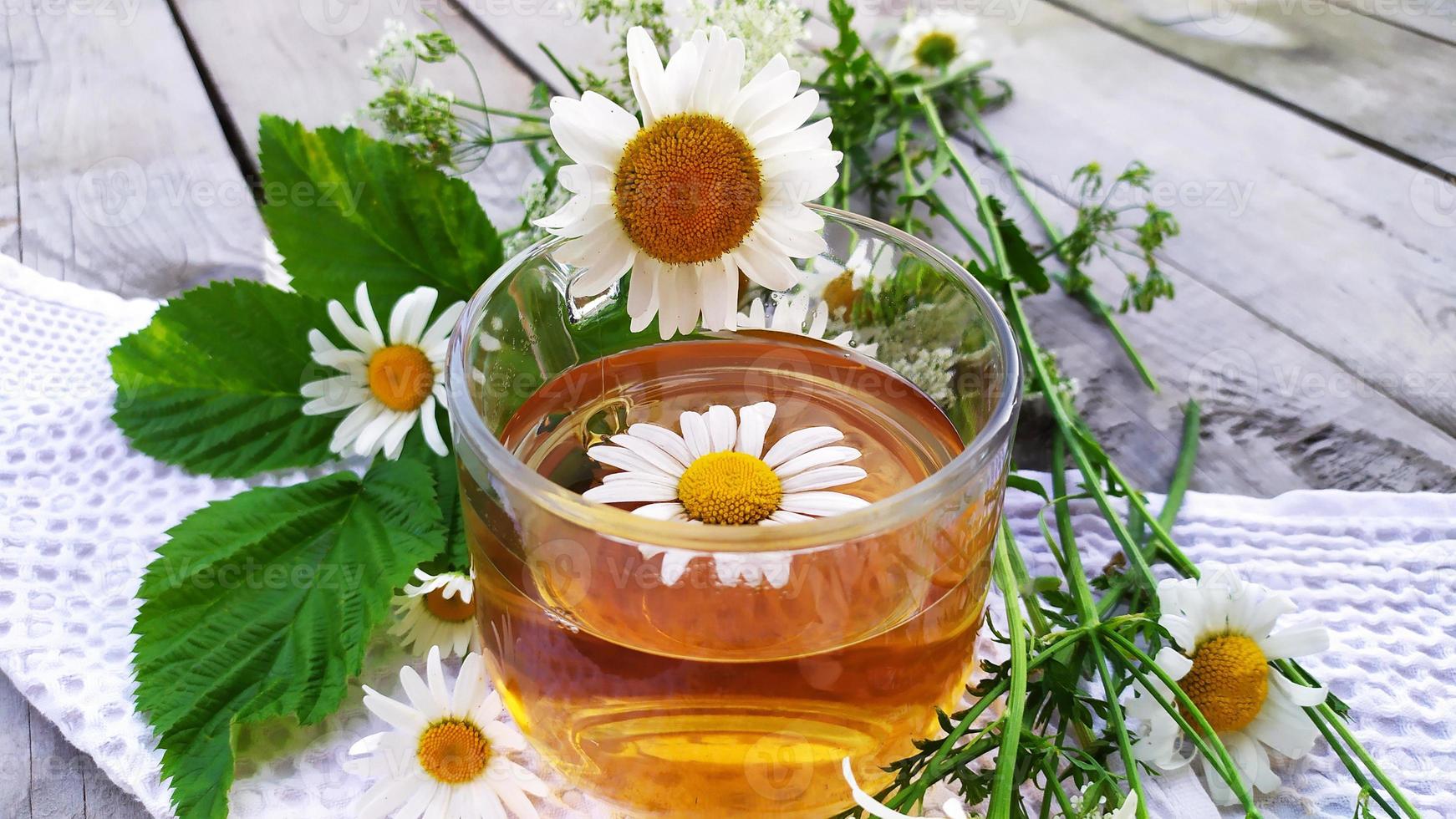kamomillte. drick med kamomillblommor. blommor och en kopp med te på en träbakgrund. foto