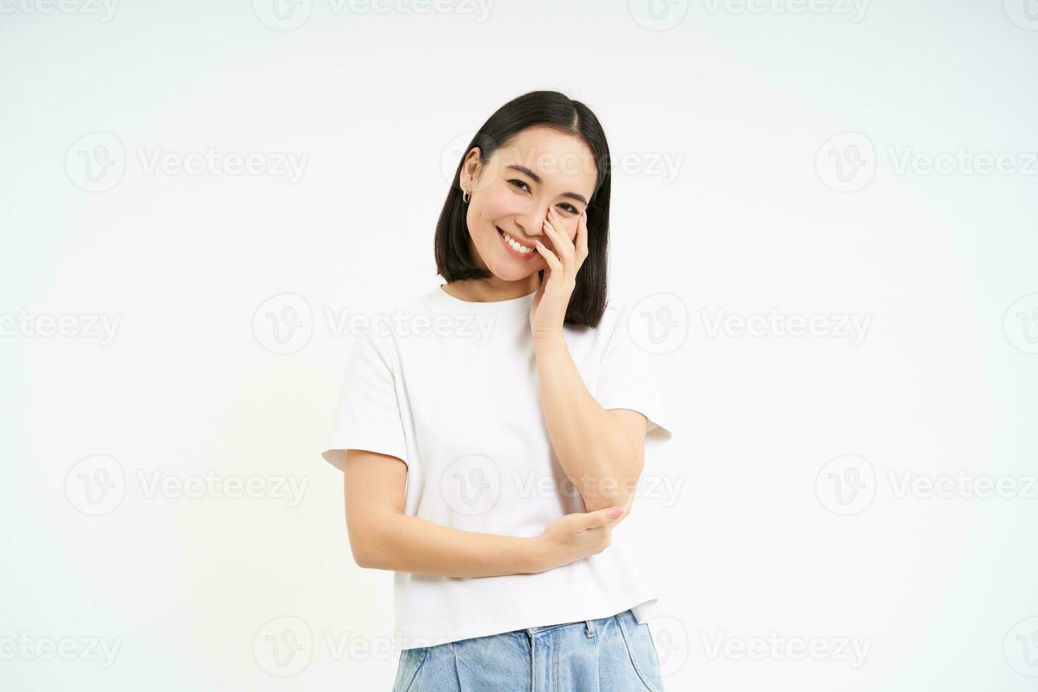 porträtt av anbud, söt ung asiatisk kvinna, ser med flörtig, dumbom ess uttryck, stående över vit bakgrund foto
