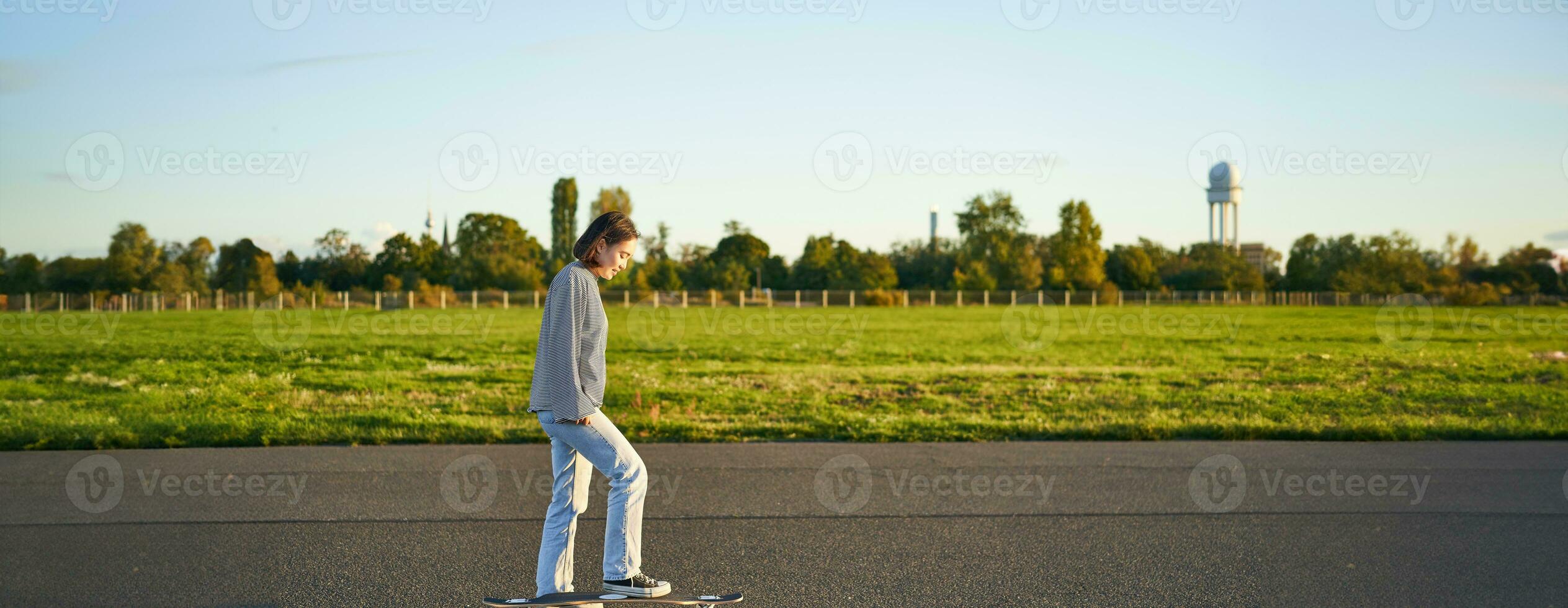 hobbies och livsstil. ung kvinna ridning skateboard. skater flicka njuter kryssning på longboard på solig dag utomhus foto