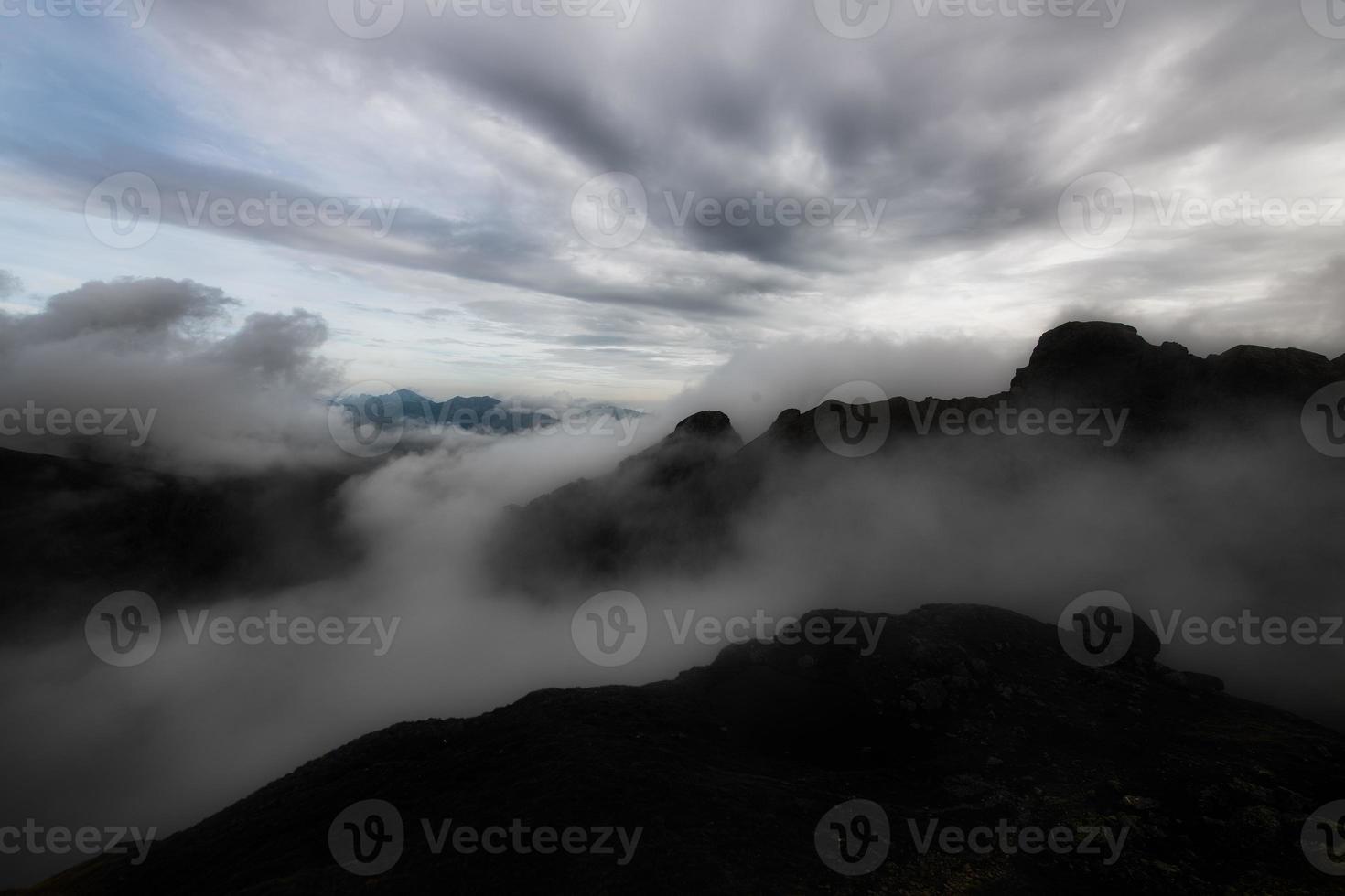 bergslandskap på kvällen med molnspel mellan topparna foto