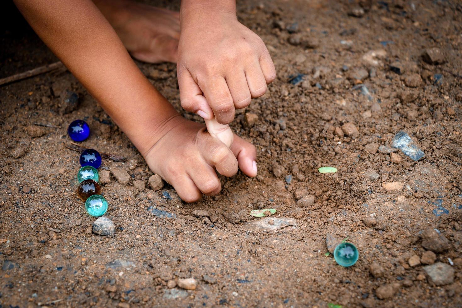 barn som spelar glasbollar på jorden foto