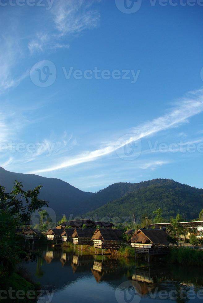 på morgonen ljusa små hyddor bredvid sjön och bergsutsikten foto