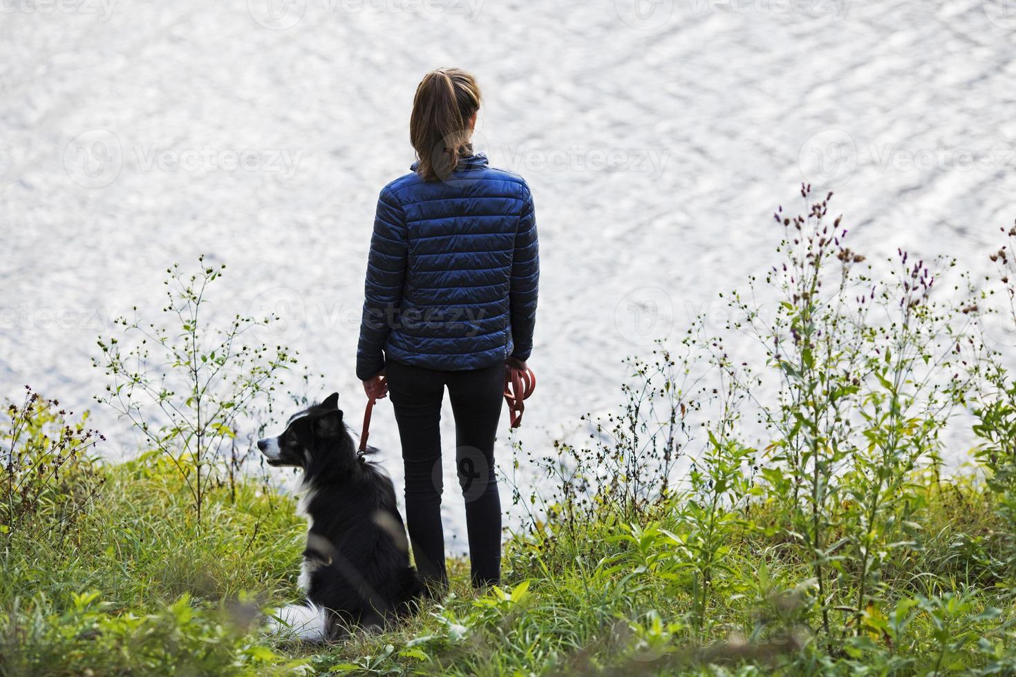 smal ung kvinna vid sjön med sin hund foto