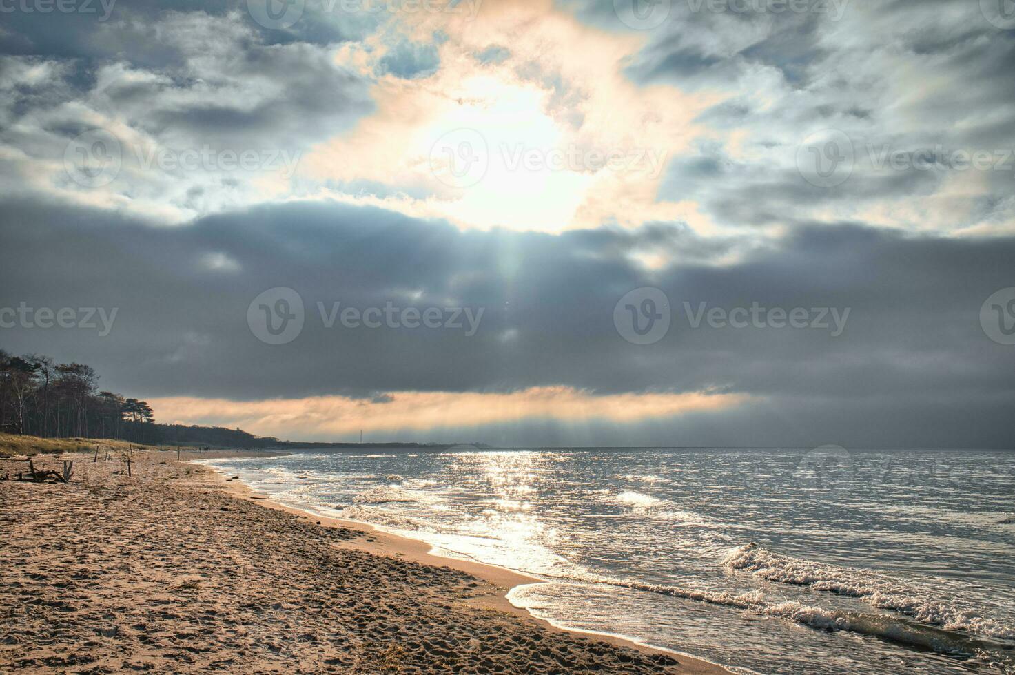 solnedgång på de väst strand på de baltic hav. vågor, strand, molnig himmel och solsken foto