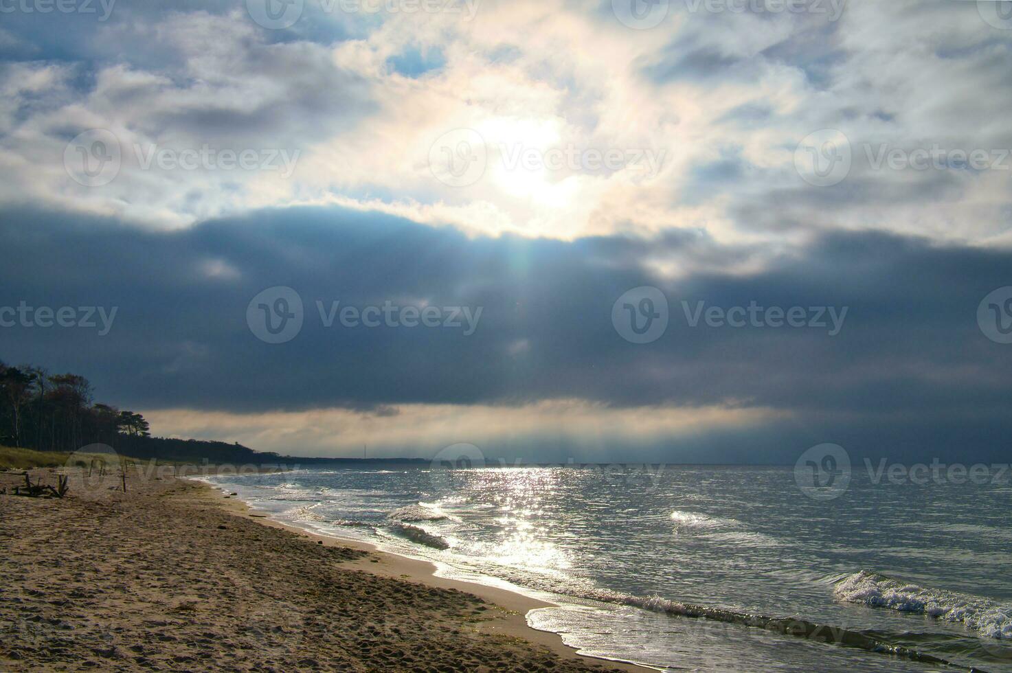 solnedgång på de väst strand på de baltic hav. vågor, strand, molnig himmel och solsken foto