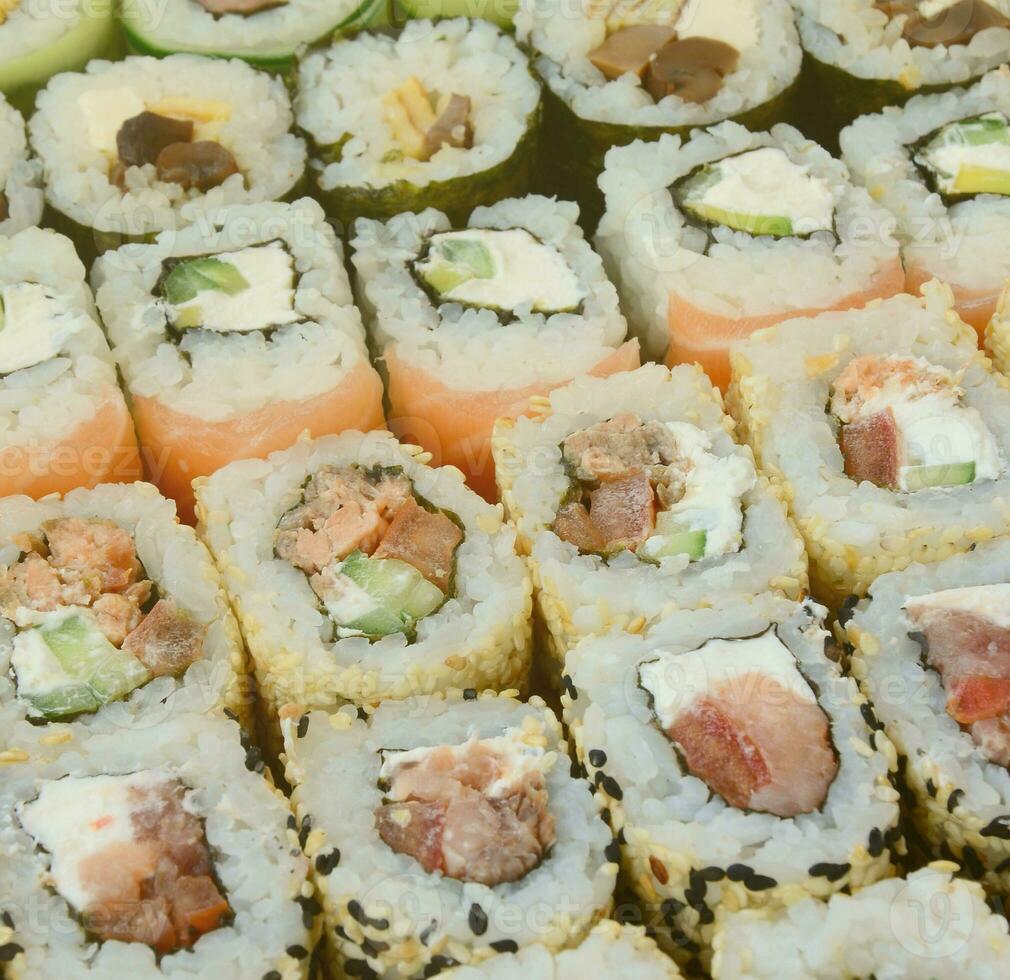 närbild av en massa av sushi rullar med annorlunda fyllningar. makro skott av kokta klassisk japansk mat. bakgrund bild foto