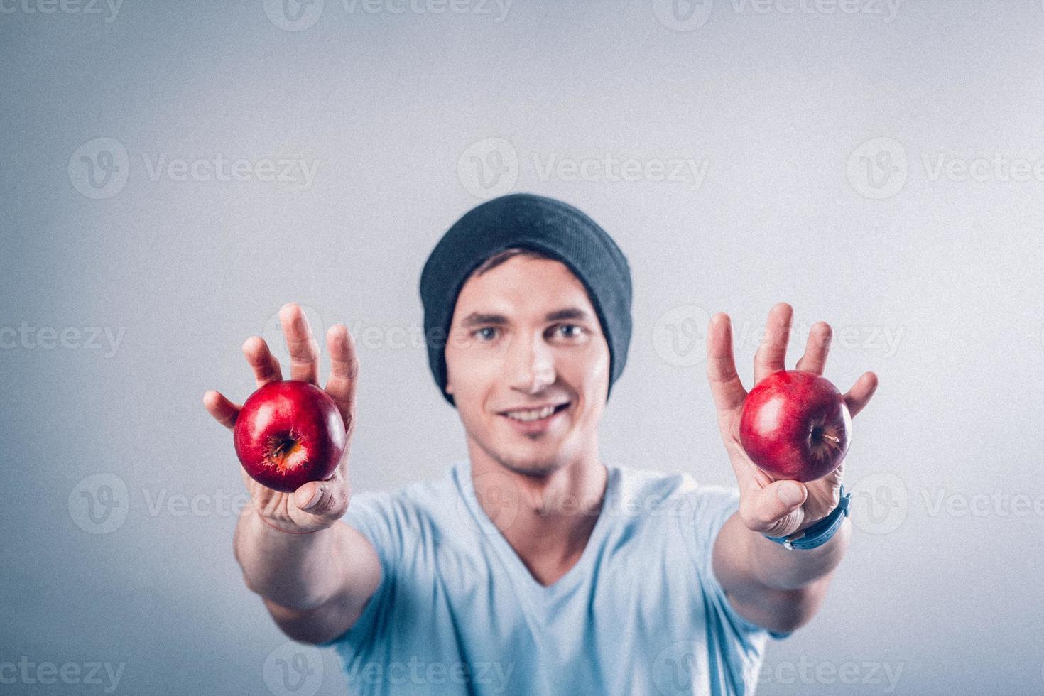 ung man håller äpplen i händerna foto